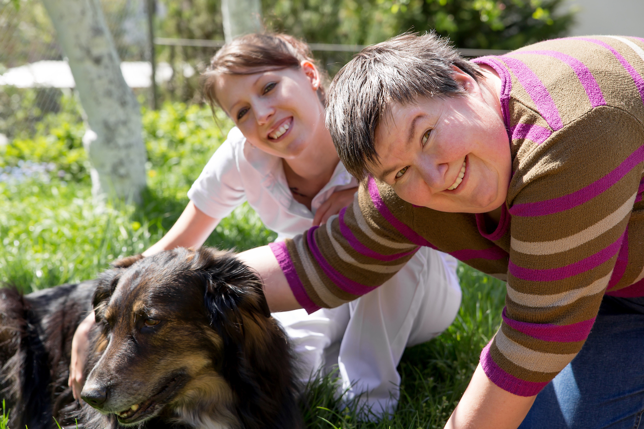 Two women with disabilities petting a dog
